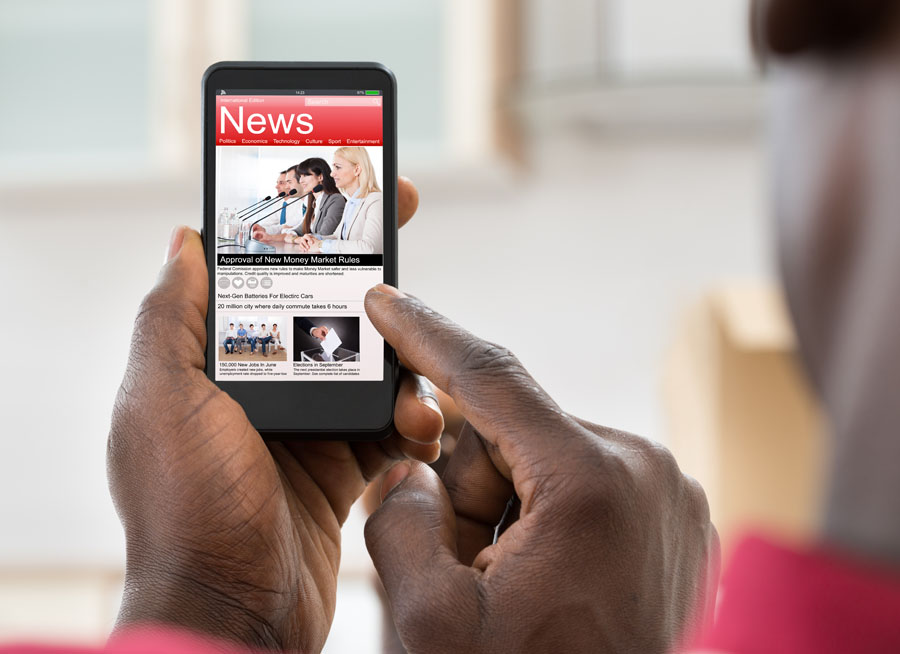 Hand holding a phone opened to a screen for news.